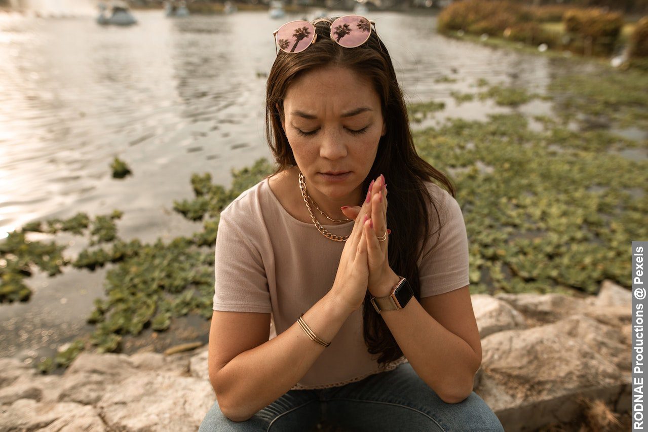 Stressed woman sitting with eyes closed on lake shore