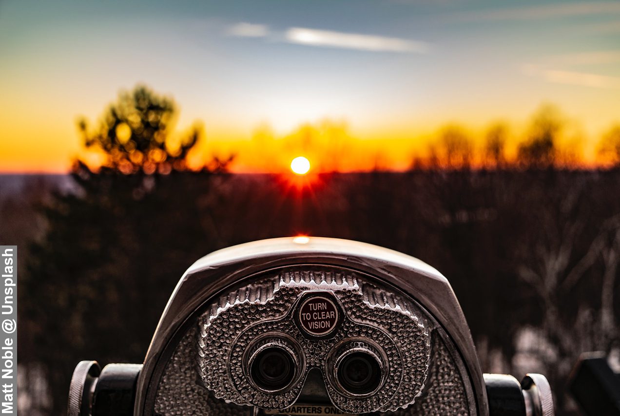 Realistic vision through a binoculars overlooking a sunset from distance
