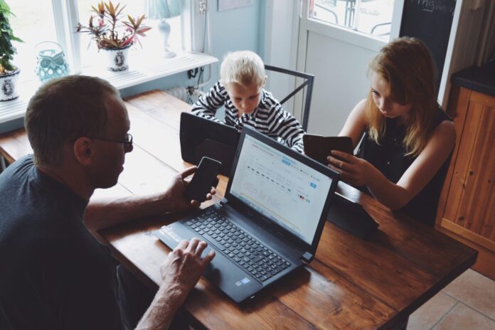 Family using multiple technology devices at table