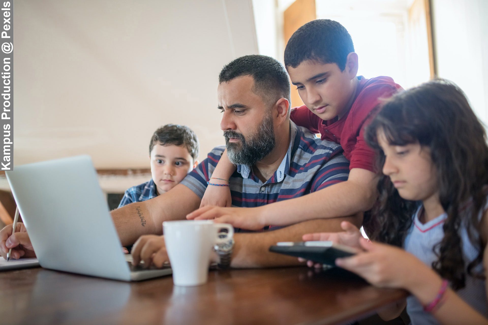 During Busy Weeks Dad Working with Kids Hanging off Him Around Table