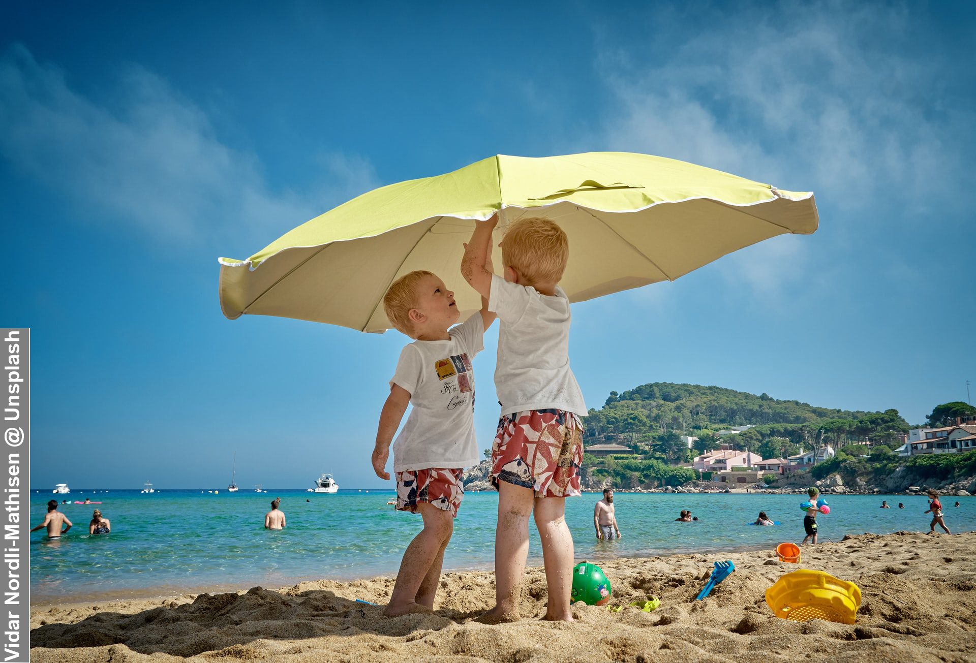 Spending Money on Family Holidays Siblings Putting Up A Parasol At A Beach