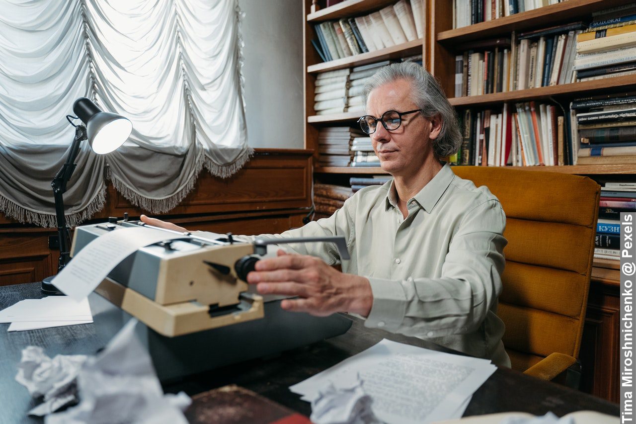 A man during unique working routines ion his work environment using a vintage typewriter