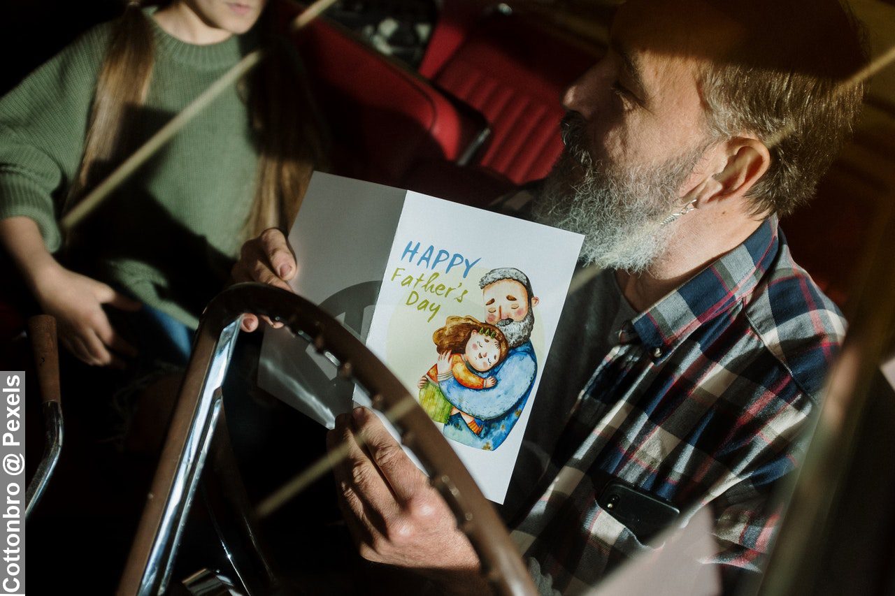 Man in Black White and Red Plaid Shirt Holding White Printer Paper with Father’s Day 2022 on it