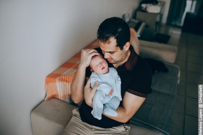 Dad settling baby in had to help teach Kids get used to sleeping by themselves