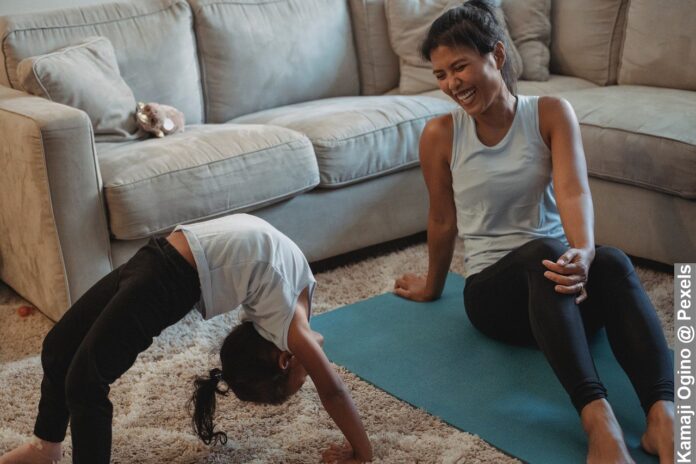 Laughing making exercise fun for kids, looking at daughter doing exercise