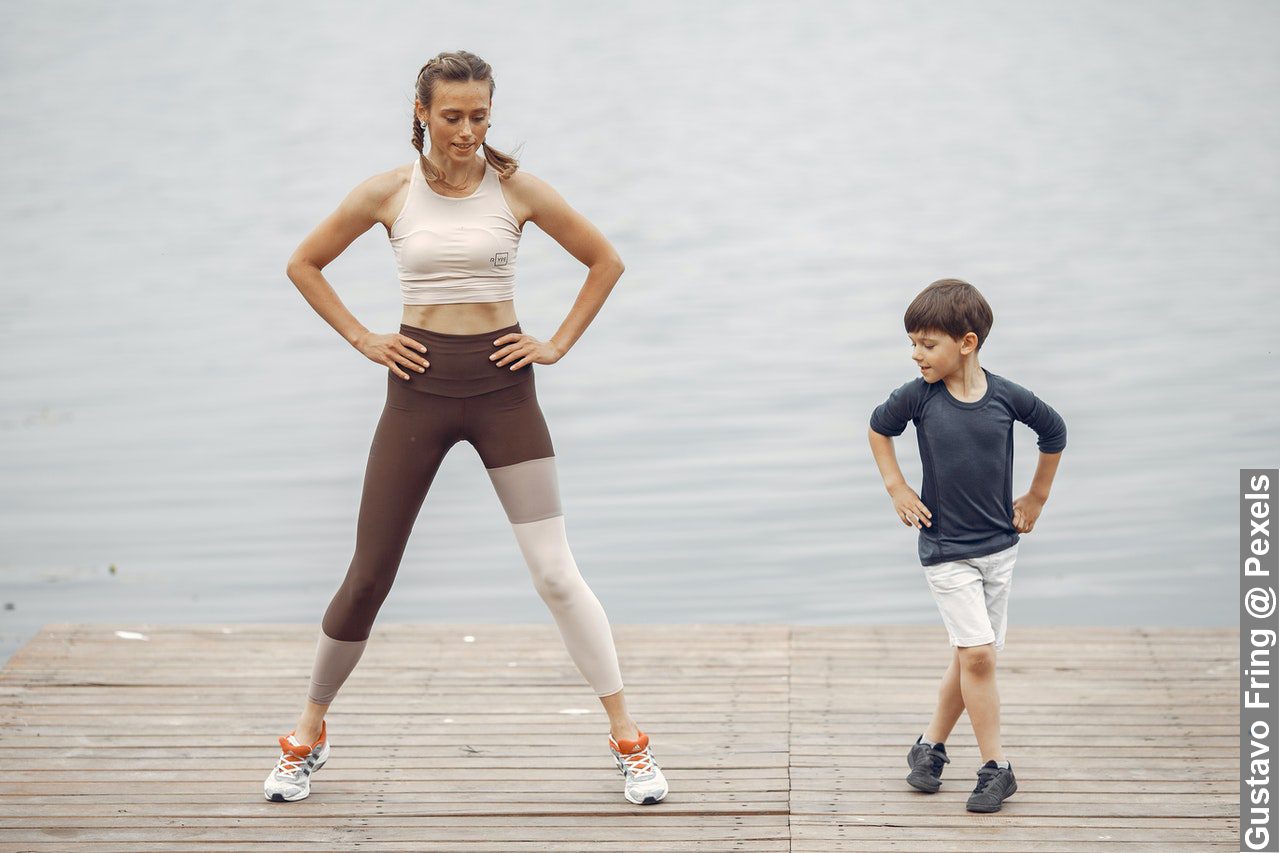 Mother making exercise fun for kids working out together by Lake Shore