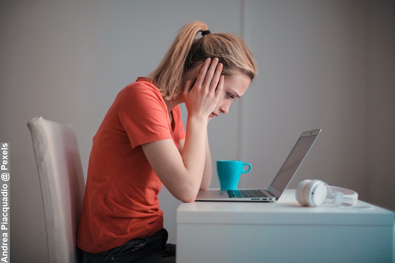 Young troubled woman using laptop at home balancing work and family