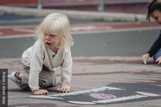 Child in a playground drawing on the floor and expressing herself