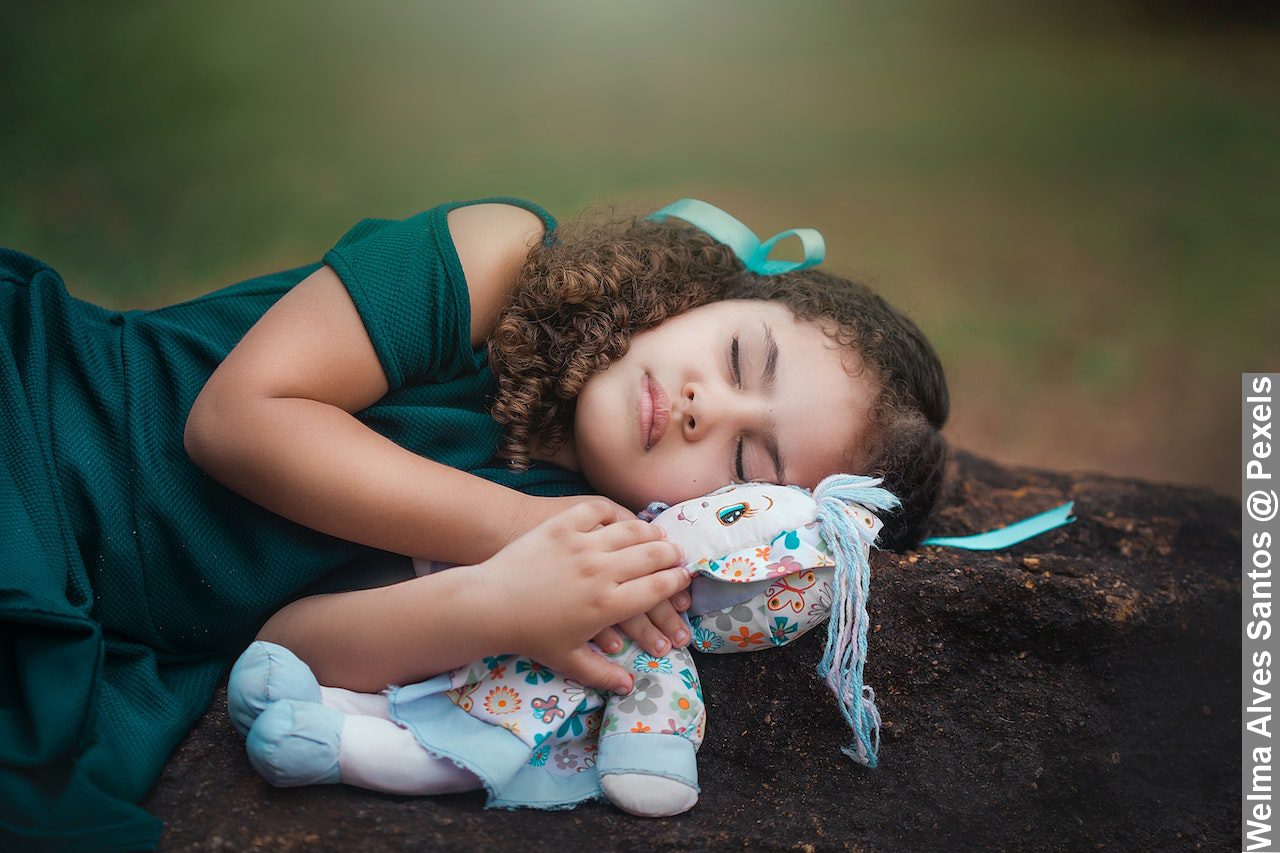 Science of sleep a cute ethnic child sleeping on ground with doll