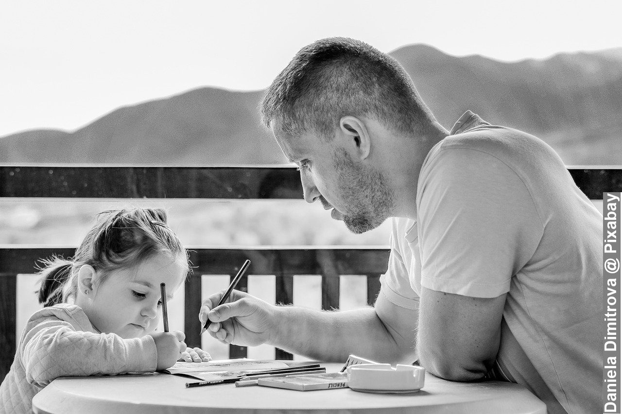 Black and white photo of father drawing with daughter outdoors