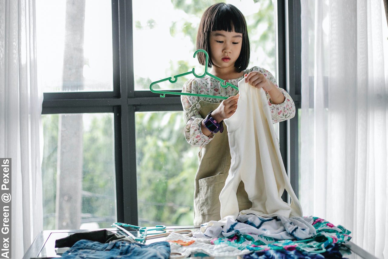 Asian little girl doing housework in room alone