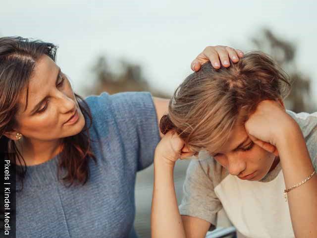 The role of a mother is to comfort her kids, daughter being comforted by mother outdoors.