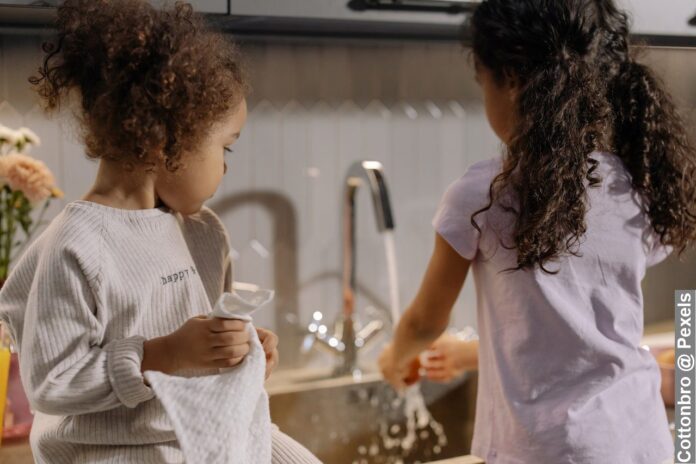 Back view of two sisters’ kids helping around the house in household chore