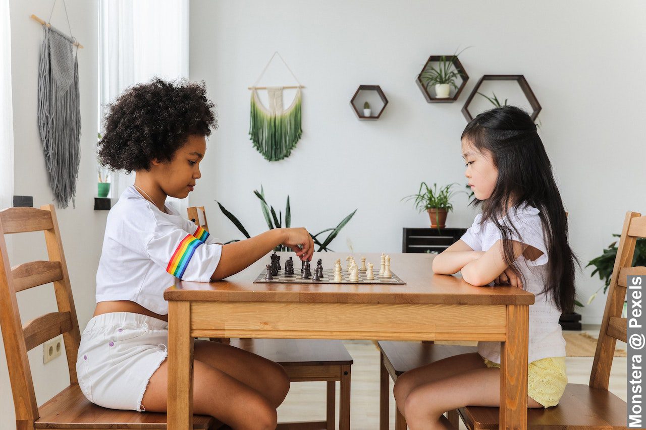 Multiethnic thoughtful girls playing chess in modern room