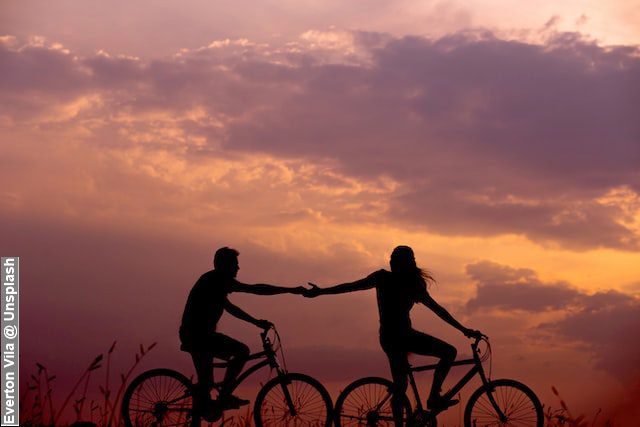 Silhouette of couple on bikes with beautiful sunset, don’t let go