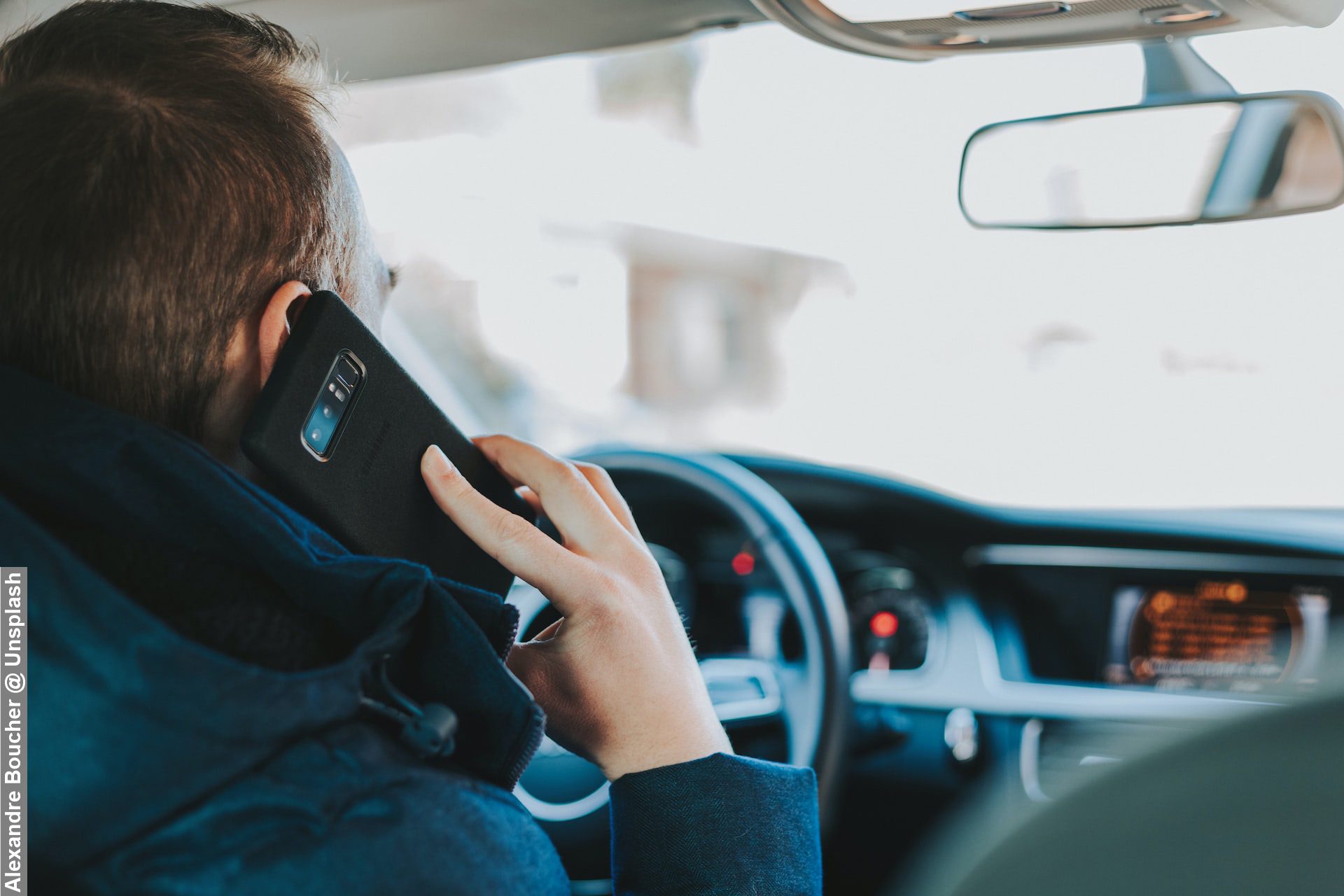 A driver a mobile phone whilst driving. Phone next to ear and he has one hand on wheel