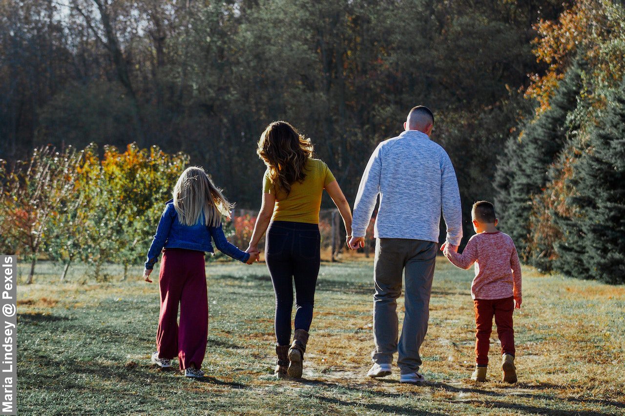 Backwards view of happy family walking in countryside