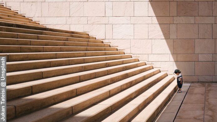 A young boy at the foot of a flight of stairs conveying the importance of having a clear and realistic vision of one's goals.