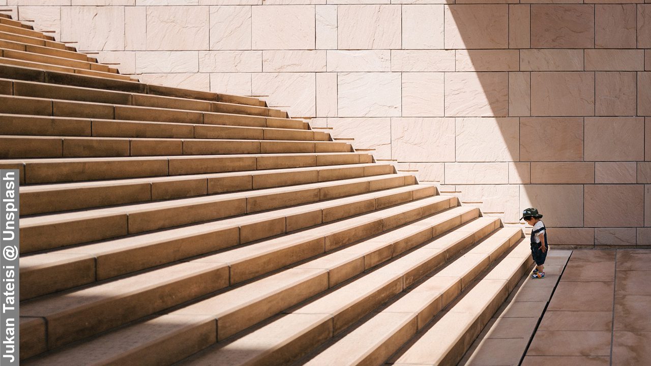 A young boy at the foot of a flight of stairs conveying the importance of having a clear and realistic vision of one's goals.
