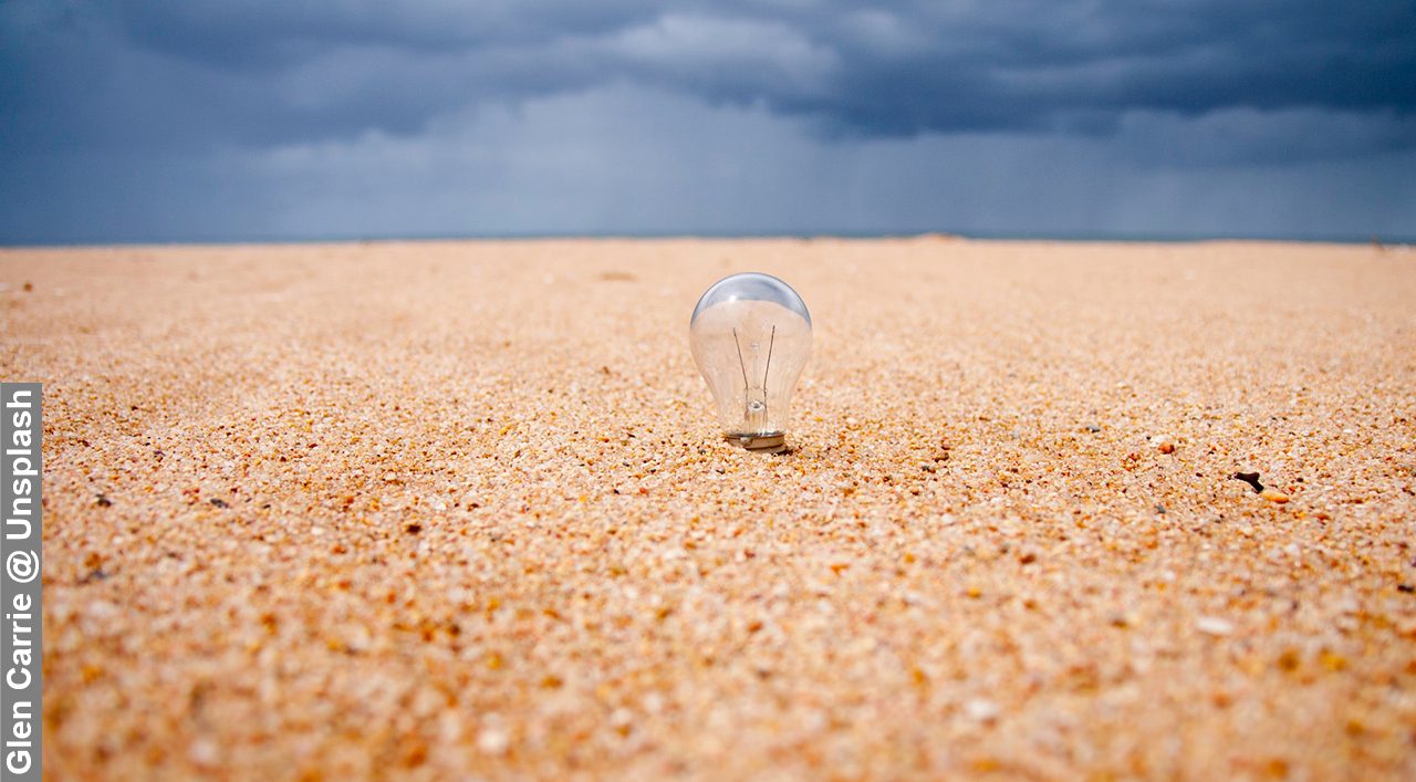 Image of a lightbulb on a beach, a "eureka" moment. Beautiful contrast in the sky