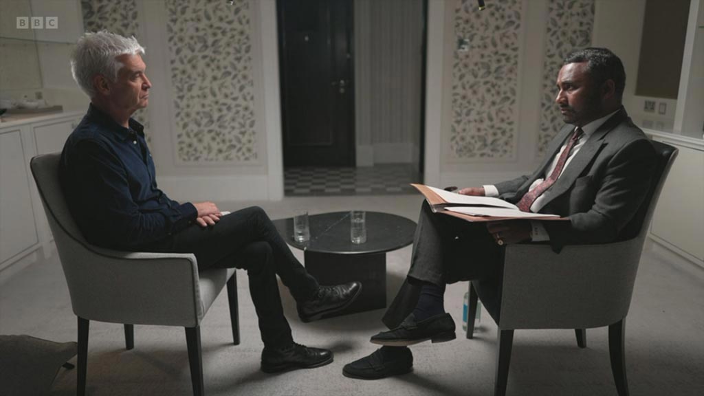 Side shot of Amol Rajan and Philip Schofield in a room with a white background, sitting across a table with water bottles. [A candid moment from the interview: Amol Rajan and Philip Schofield engaged in a deep conversation.]