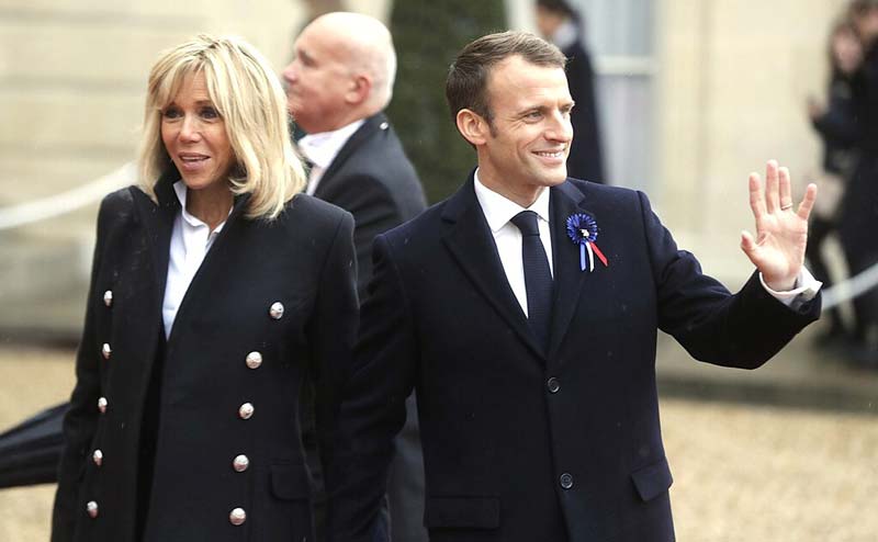 Macrons Sue Candace Owens case protagonists Emmanuel and Brigitte Macron photographed together at official Elysee Palace event before legal controversy.